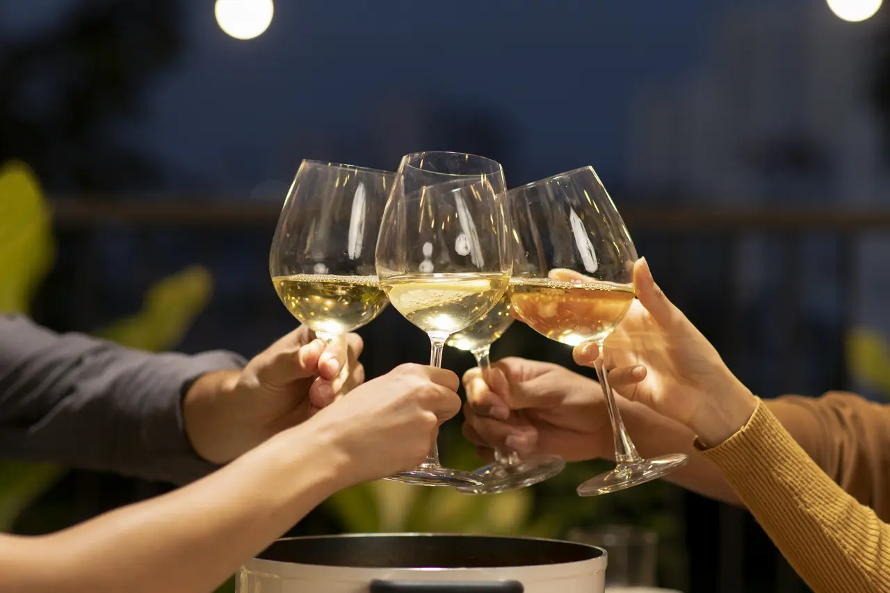 Personas que se sostienen de la mano copas de vino mientras cenan erizos de mar