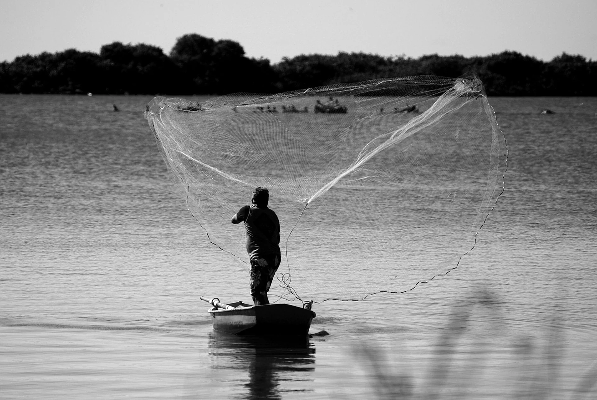 Pescador echando las redes para capturar pescado fresco para venderlo en la lonja de pesca.
