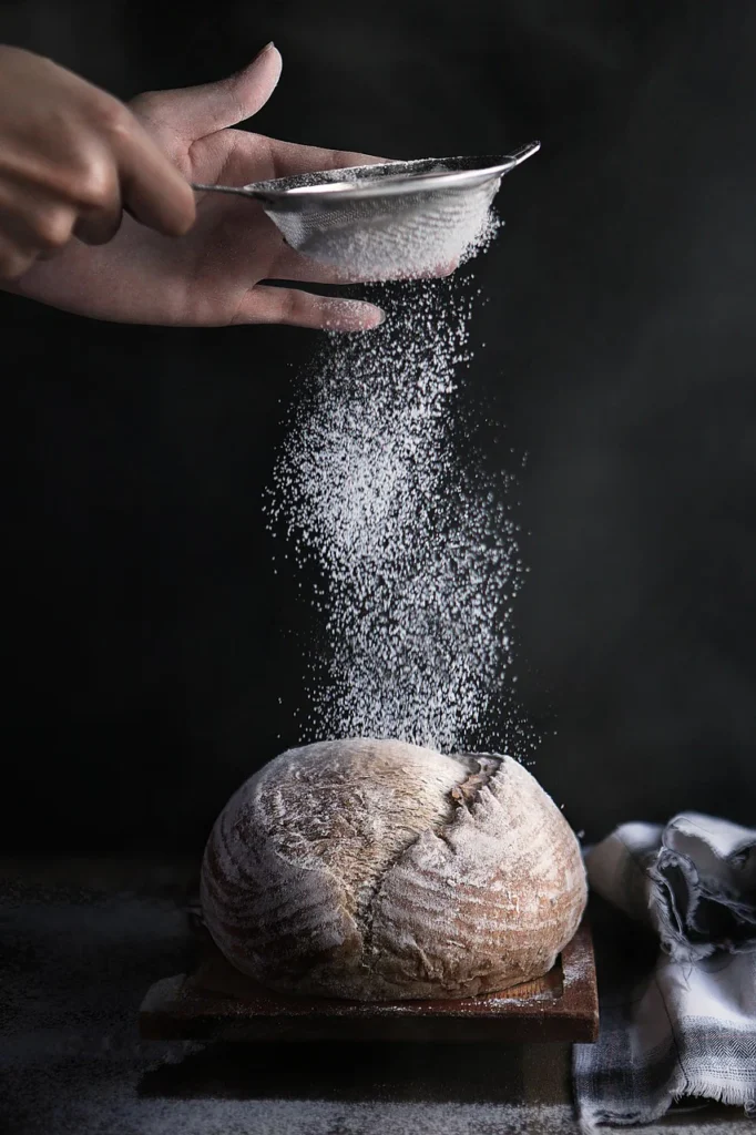 Espolvoreando harina fina sobre un pan de masa madre con delicadeza